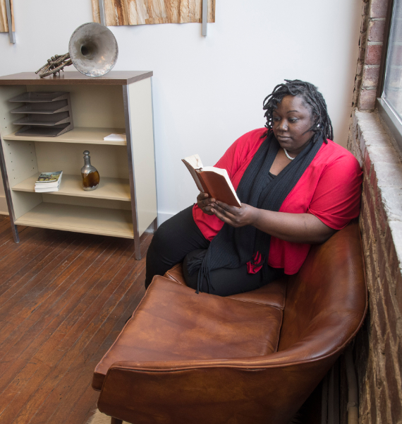 A theology student reads a book on a couch