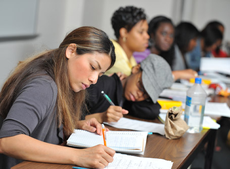 A row of students seated at a table taking notes