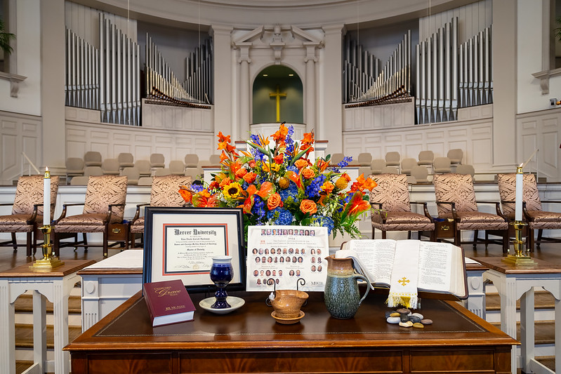 Communion table in the sanctuary of a church with a chalice, flowers, water pitcher, and oil lamp on it