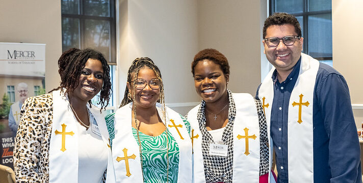 Group of 4 students of color smiling and wearing stoles