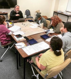 Group of students with a professor around a table in a discussion
