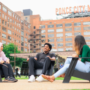Three students sitting and talking outside a building