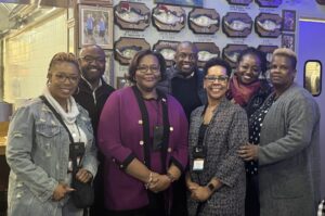 Five McAfee students with their professor and a staff member posing in a restaurant 