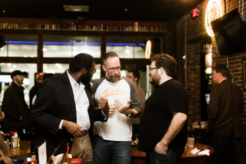 Three men standing and talking inside a building