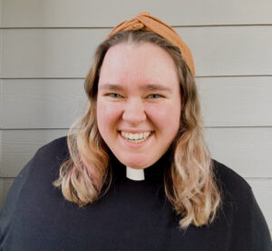 Courtney Henry - white woman with blonde hair smiling, wearing a ministerial collar and a black top