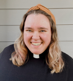 Courtney Henry - white woman with blonde hair smiling, wearing a ministerial collar and a black top